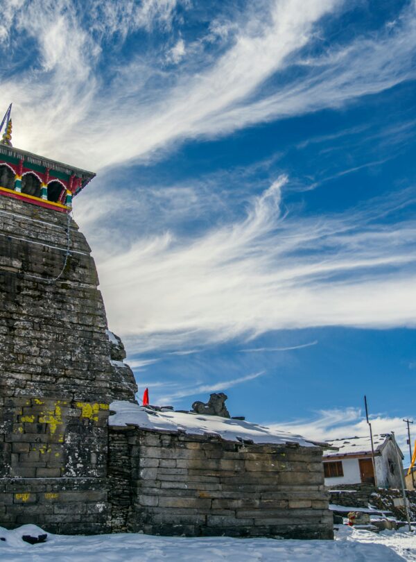Snow-covered temple with vibrant decorations under a bright blue sky.
