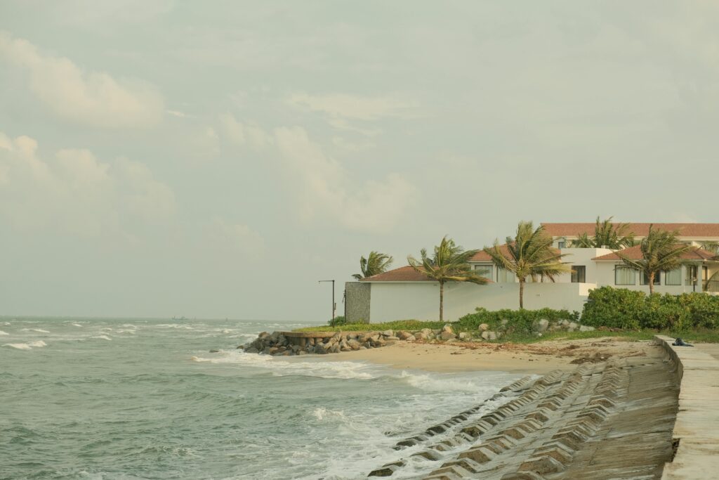 Peaceful view of a coastal resort in Hội An, Vietnam with gentle waves and palm trees.