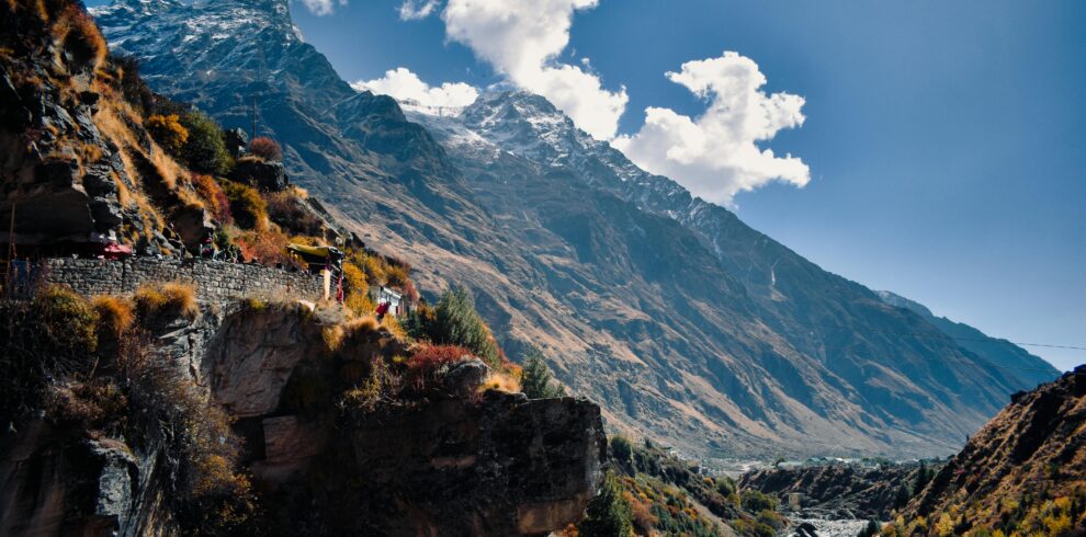 Scenic view of majestic mountains and stream in Kedarnath, India, under a clear blue sky.