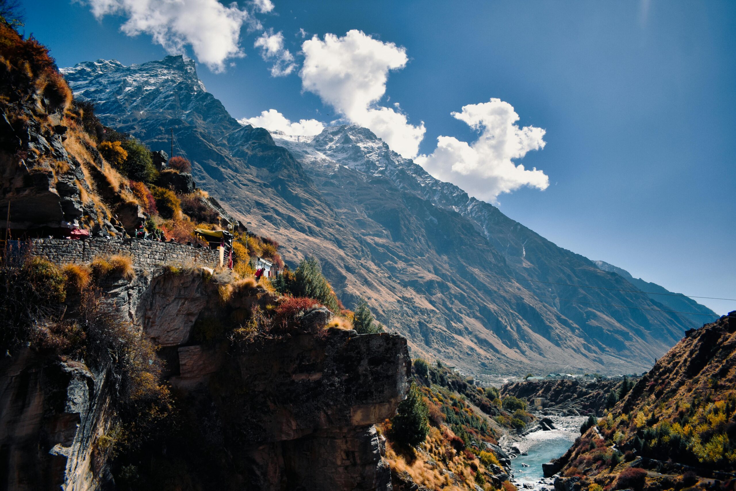 Scenic view of majestic mountains and stream in Kedarnath, India, under a clear blue sky.