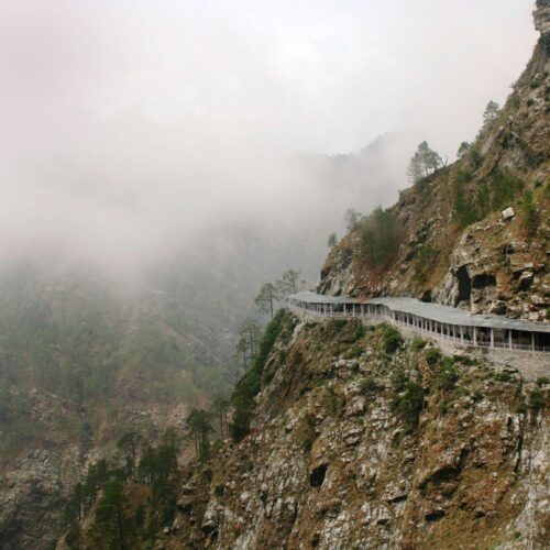 Discover a serene foggy mountain road winding through rocky terrain in a natural landscape.
