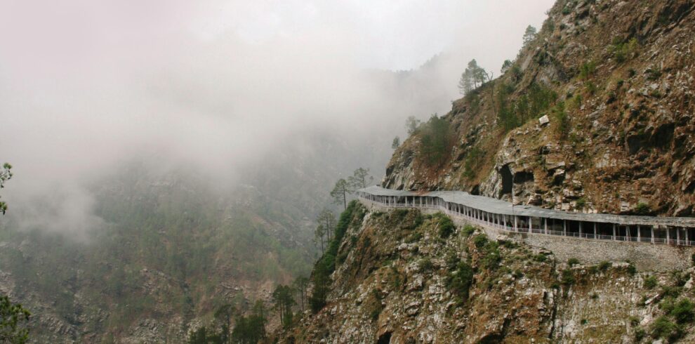 Discover a serene foggy mountain road winding through rocky terrain in a natural landscape.